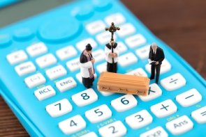 Funeral costs Figures of priest, altar boy and mourners and coffin on a calculator