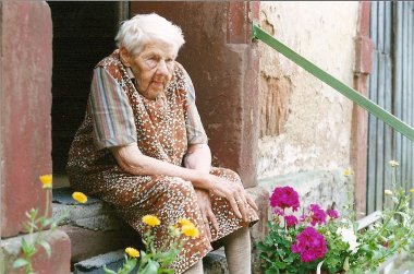 Maria Schmitt in summer 1999 Colour photo of 91-year-old Maria Schmitt in front of her house with colourful flowers.
