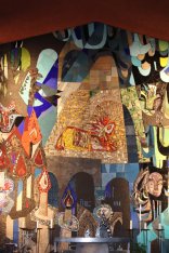 Mosaic of the Old Arm in the Church of Our Lady of Peace A large, colourful, abstract mosaic behind a church altar.