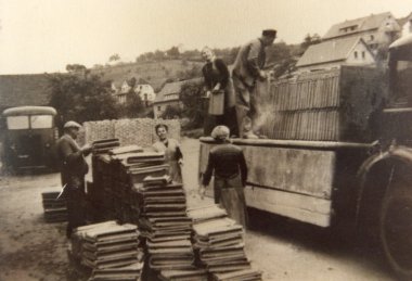 Dawo brickworks, loading of bricks Black and white photo of bricks being loaded from a stack onto a small loading area.