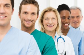 several people with professions in the healthcare sector stand behind each other and look into the camera