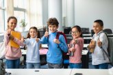 Schoolchildren give a thumbs-up to the camera