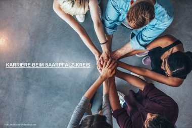 Specialists and managers People lay their hands on each other in a circle and Karriere beim Saarpfalz-Kreis reads