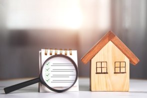 Contrôle de la construction Une loupe sur un bloc avec une liste cochée et une maison en bois