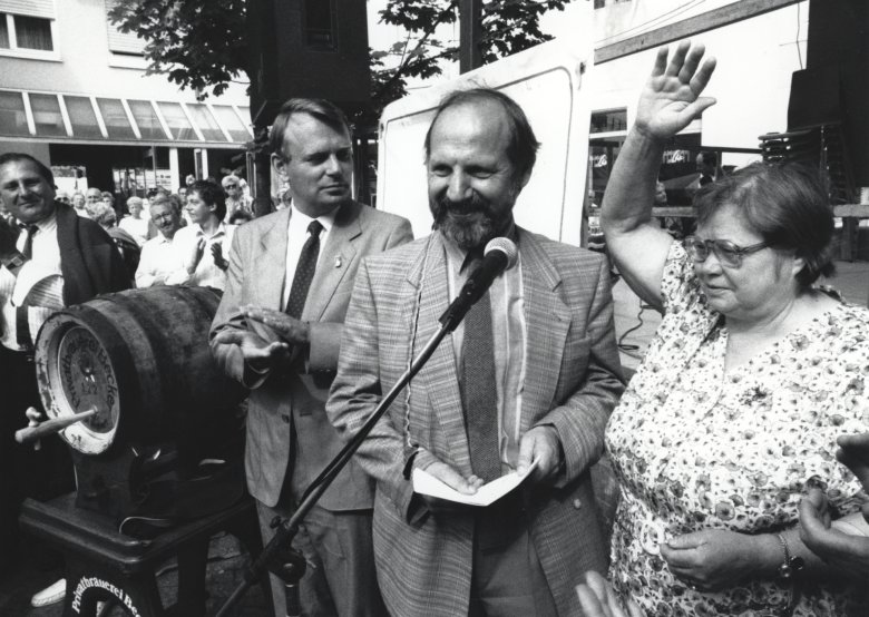 Photo en noir et blanc de deux hommes et d'une femme devant un micro.