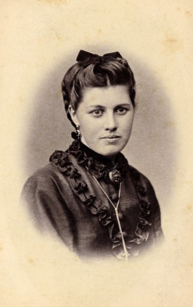 Portrait Heim/Ritter 2 Portrait en noir et blanc de la tête à la poitrine d'une jeune femme avec un nœud dans les cheveux.