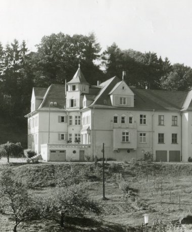 Photo en noir et blanc d'une villa de quatre étages avec un jardin à l'avant.