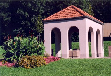 Photo en couleur d'une reconstitution moderne d'un lavoir, située dans un pré verdoyant.