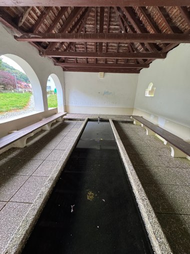 Photo en couleur de l'intérieur d'un lavoir comportant, au centre, un bassin rectangulaire allongé et peu profond.
