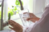 Une femme remplit son verre au robinet