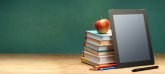 Un tavolo con libri, una mela, penne e un tablet