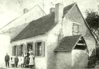 Foto Schwaz-Weiß di una famiglia in piedi davanti a una casa.
