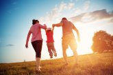 Aiuto per bambini, giovani e famiglie I genitori tengono ciascuno la mano del proprio bambino e lo cullano.