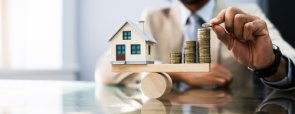 Broker di prestiti immobiliari Bilancia con una casa a destra e monete a sinistra