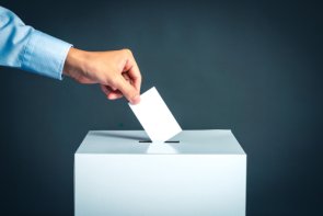 Elezioni del consiglio distrettuale Un uomo getta una scheda elettorale in un'urna.
