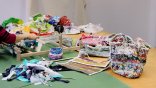 Projektowanie tekstyliów i upcykling Kobieta tka na krośnie, a wokół niej leżą różne tkaniny
