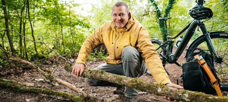 Zarządzanie trasami turystycznymi Rowerzysta usuwa gałęzie z leśnej ścieżki