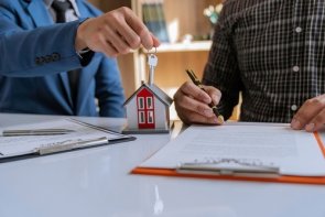Pośrednictwo Mężczyzna w garniturze wręcza klucz mężczyźnie podpisującemu umowę