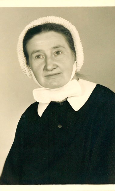 Portre Johanna Folz Johanna Folz'un koyu renk üstü, beyaz bonesi ve yakasıyla siyah beyaz fotoğrafı.