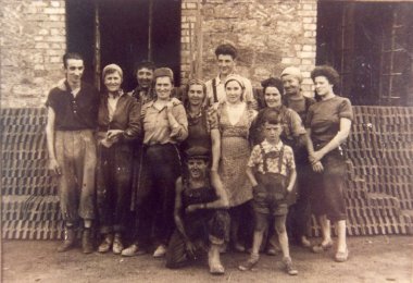 Працівники цегельного заводу в Даво Чорно-біла фотографія дванадцяти робітників цегельного заводу на тлі цегли та будівлі.