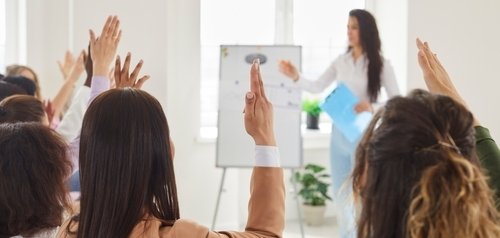 Люди в аудиторії мають запитання і піднімають руки. Люди в аудиторії мають запитання і піднімають руки.