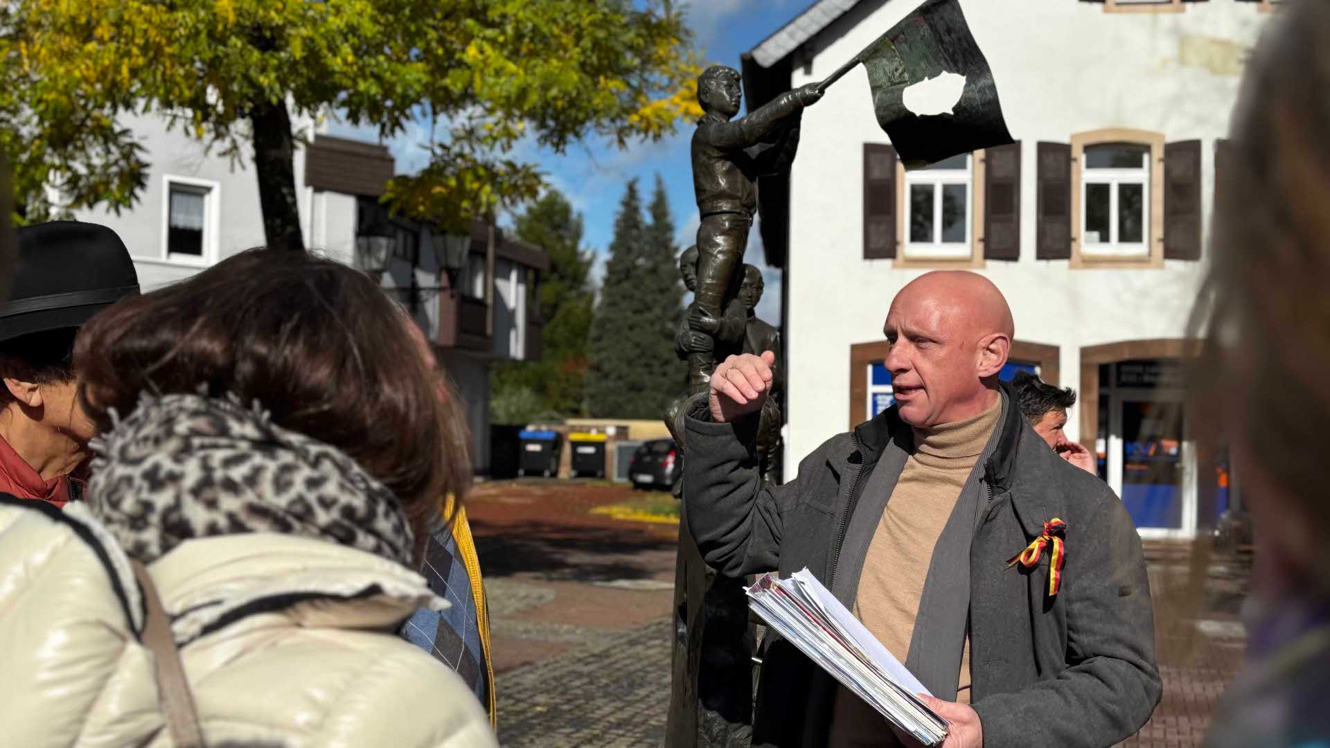 Klaus Friedrich erklärt am Homburger Freiheitsbrunnen dessen Symbolik zum Vormärz und Mauerfall 1989 und damit verbundene Bezüge nach Amerika, Foto: Beate Ruffing