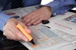 Informationen für Arbeitssuchende Ein Mann streicht Jobangebote in der Zeitung mit Textmarker an