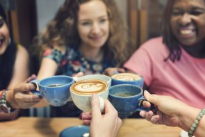 mehrere Frauen stoßen mit Kaffee an