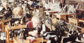 Schuhfabrik Blieskastel Farbfoto Innenansicht einer Fabrik. Frauen sitzen in Reihen an Nähmaschinen.