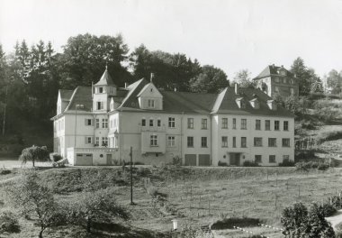 Schwarz-Weiß-Foto einer viergeschossigen Villa mit vorgelagertem Garten.