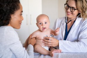 Ärztin untersucht ein Baby und die Mutter sitzt nebendran