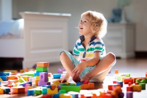 lachendes Kind sitzt zwischen Bauklötzen