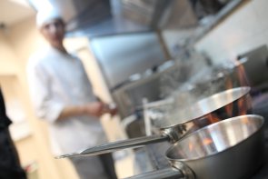 Küche mit Töpfen und Pfannen und ein Koch im Hintergrund
