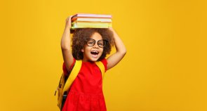 Lachendes Kind balanciert Bücher auf ihrem Kopf