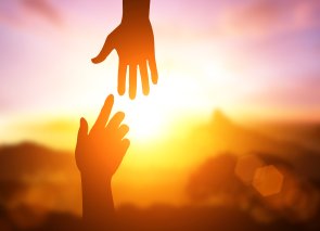 Hospiz - und Palliativnetz Saarpfalz Zwei Hände probieren einander zu erreichen in der Sonne