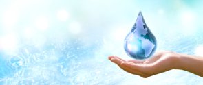 Eine Hand hält einen großen Wassertropfen