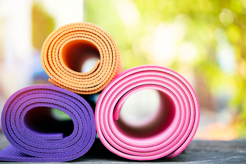 Es sind drei eingerollte Yogamatten in verschiedenen Farben zu sehen.