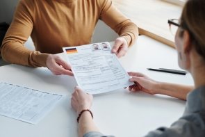 Einbürgerung Ein Mann übergibt einer Frau einen Einbürgerungsantrag
